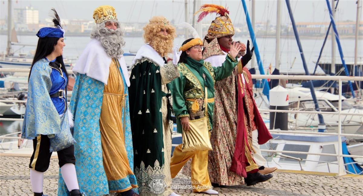 Pessoas com trajes históricos à beira-mar.