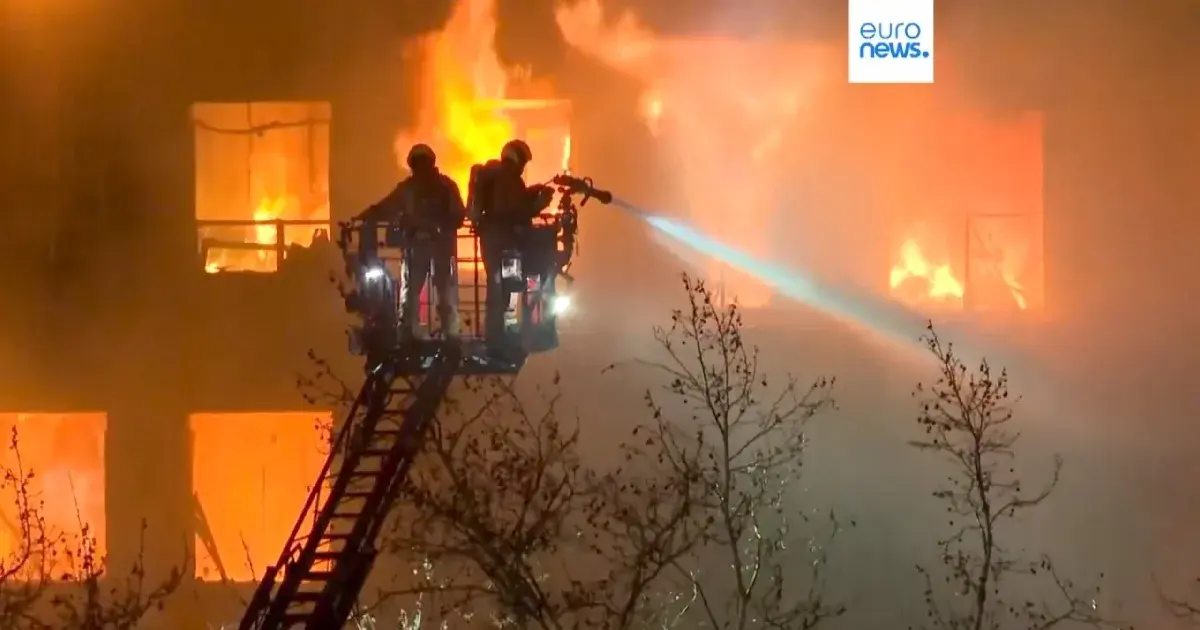 Bombeiros combatem incêndio urbano à noite.