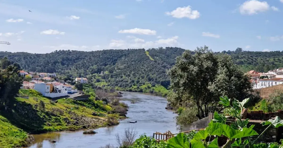 Paisagem fluvial com vegetação e casario em Portugal.
