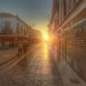 Pôr do sol em rua tranquila com pedestres.