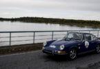 Porsche clássico azul junto a lago.