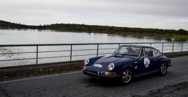 Porsche clássico azul junto a lago.