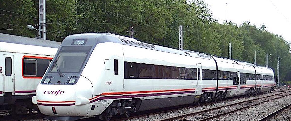 Comboio Renfe moderno em linha ferroviária arborizada.